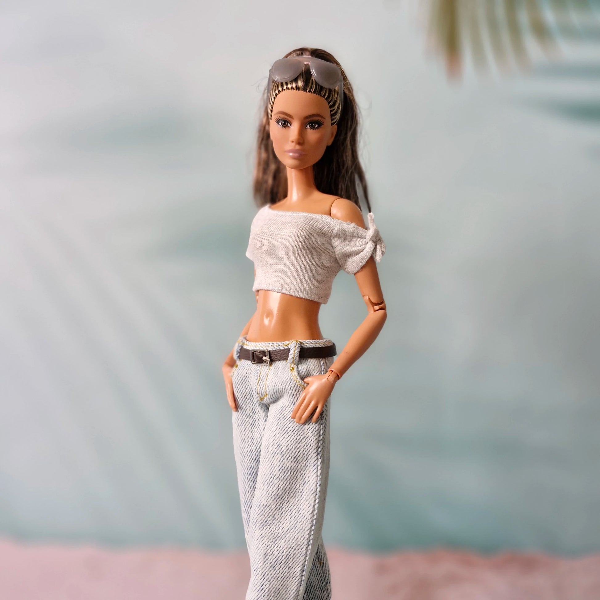 Barbie doll wearing a white off-shoulder top and patterned pants with a blurred background