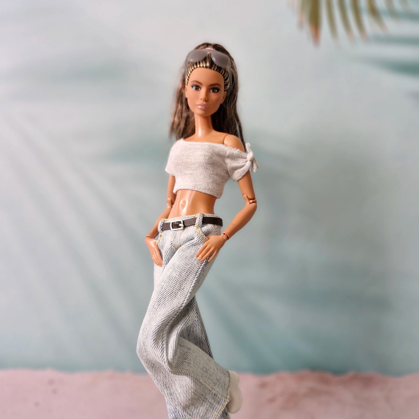 Barbie doll wearing a white top and patterned pants with a blurred background