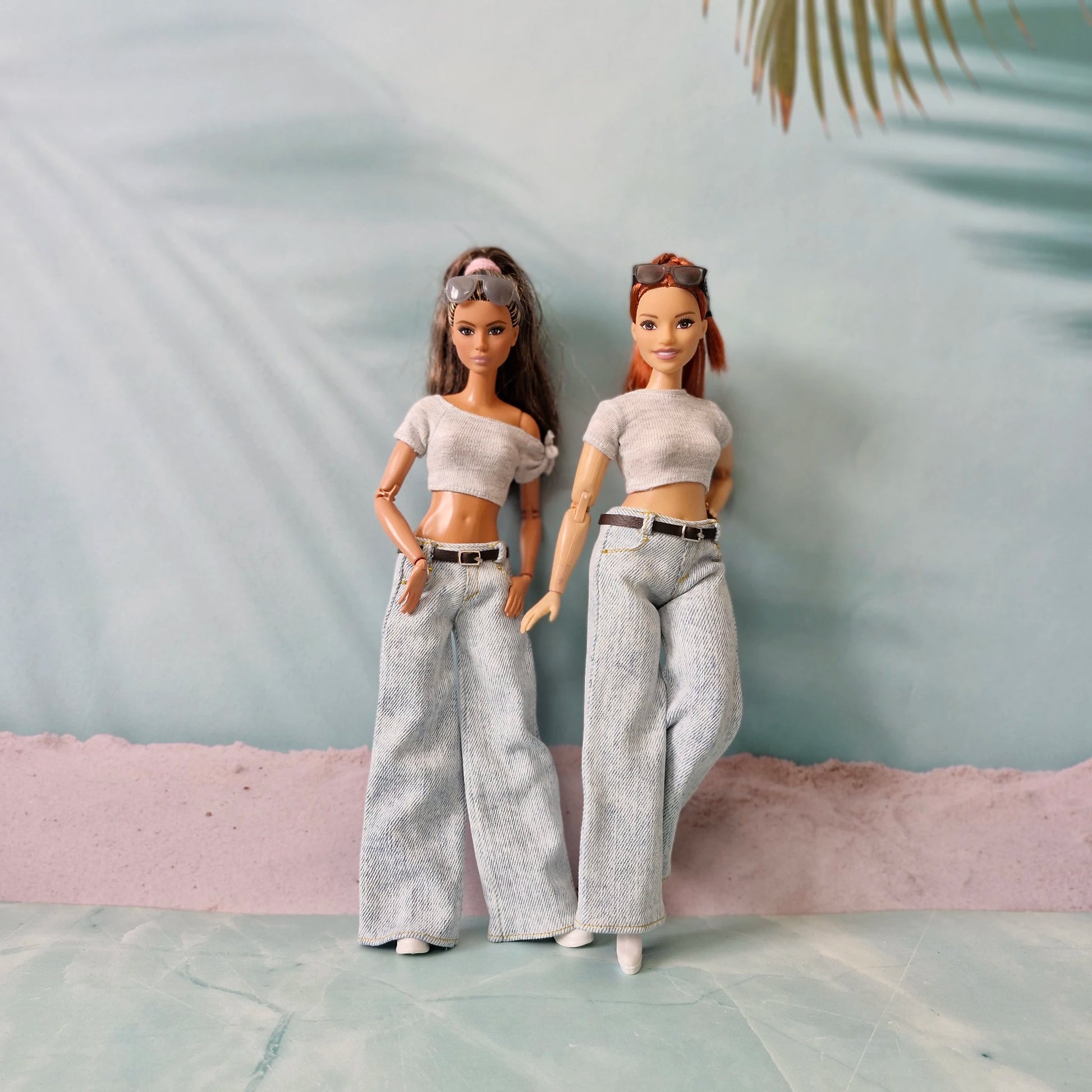 Two dolls wearing matching outfits with a neutral background