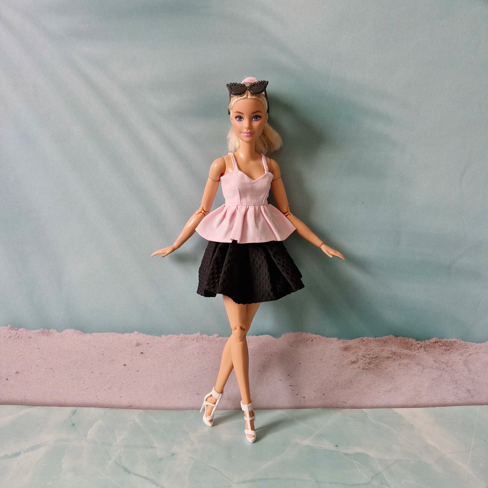 Barbie doll wearing a pink top and black skirt on a plain background