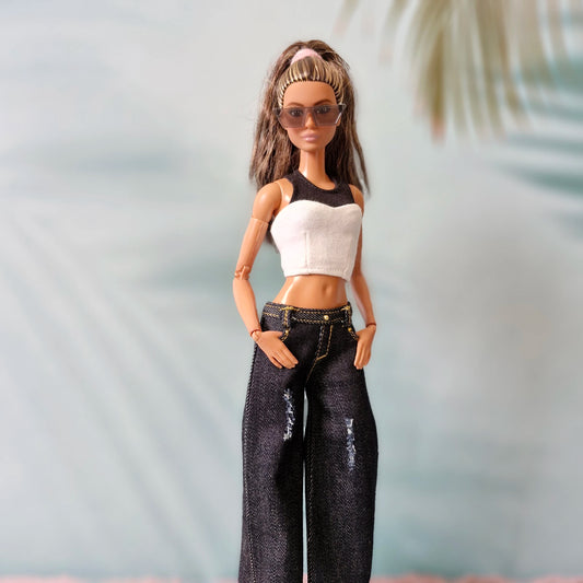 Barbie doll wearing a black and white top and jeans with a blurred background