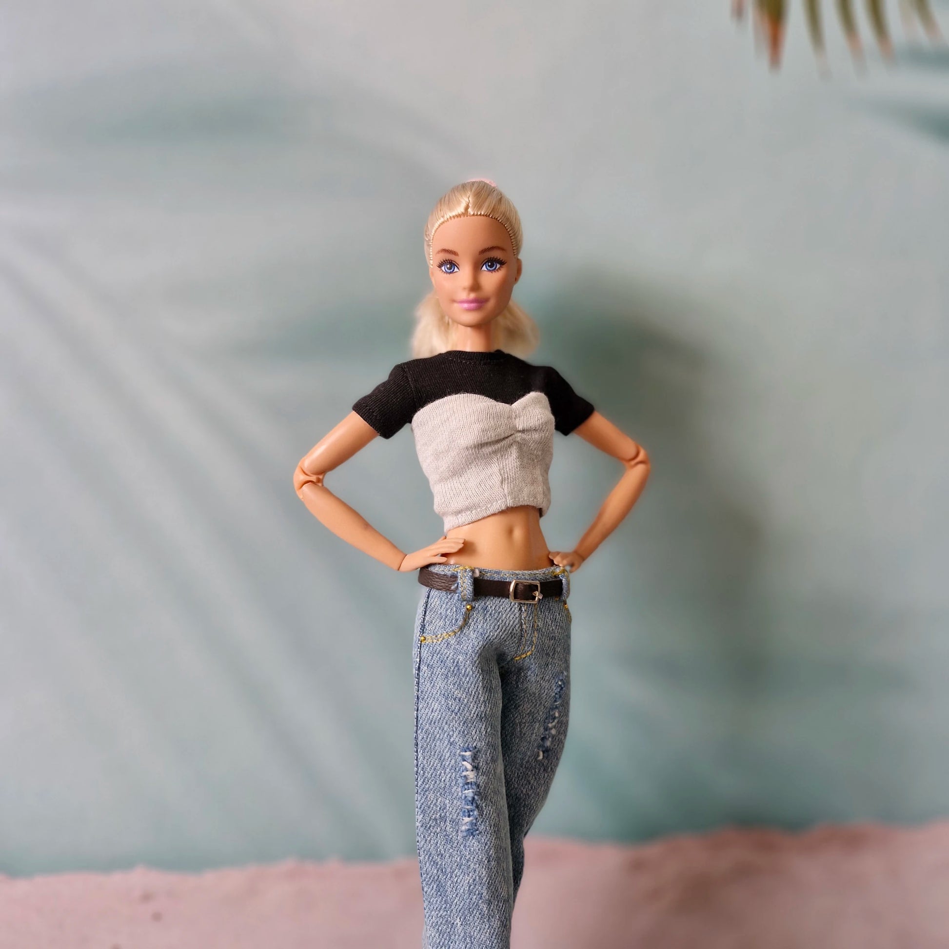 Barbie doll wearing a black and white crop top and blue jeans against a blurred background