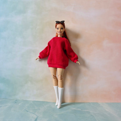Barbie doll wearing a red sweater and white boots against a gradient background