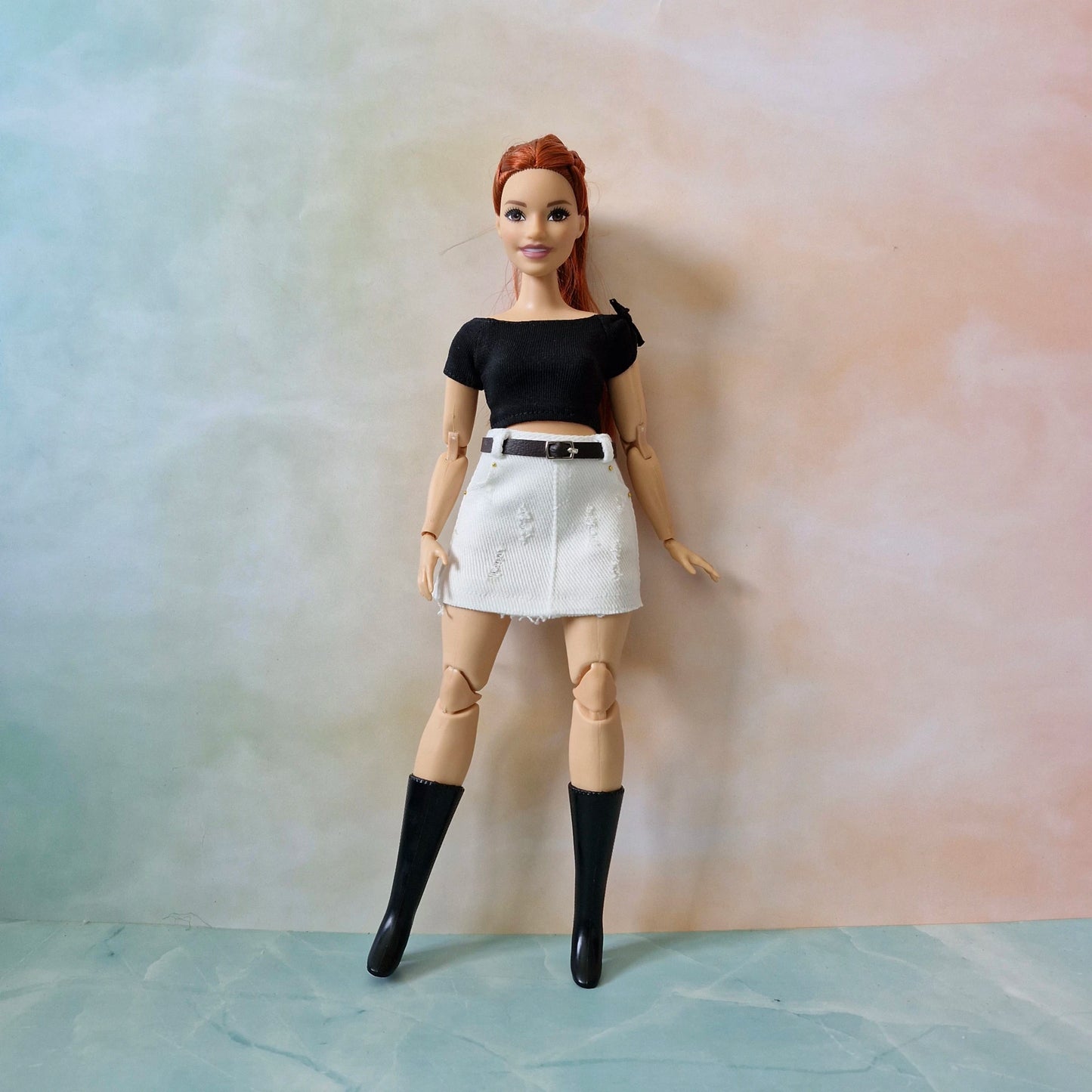 Full body of Barbie curvy doll in black top and white skirt with boots