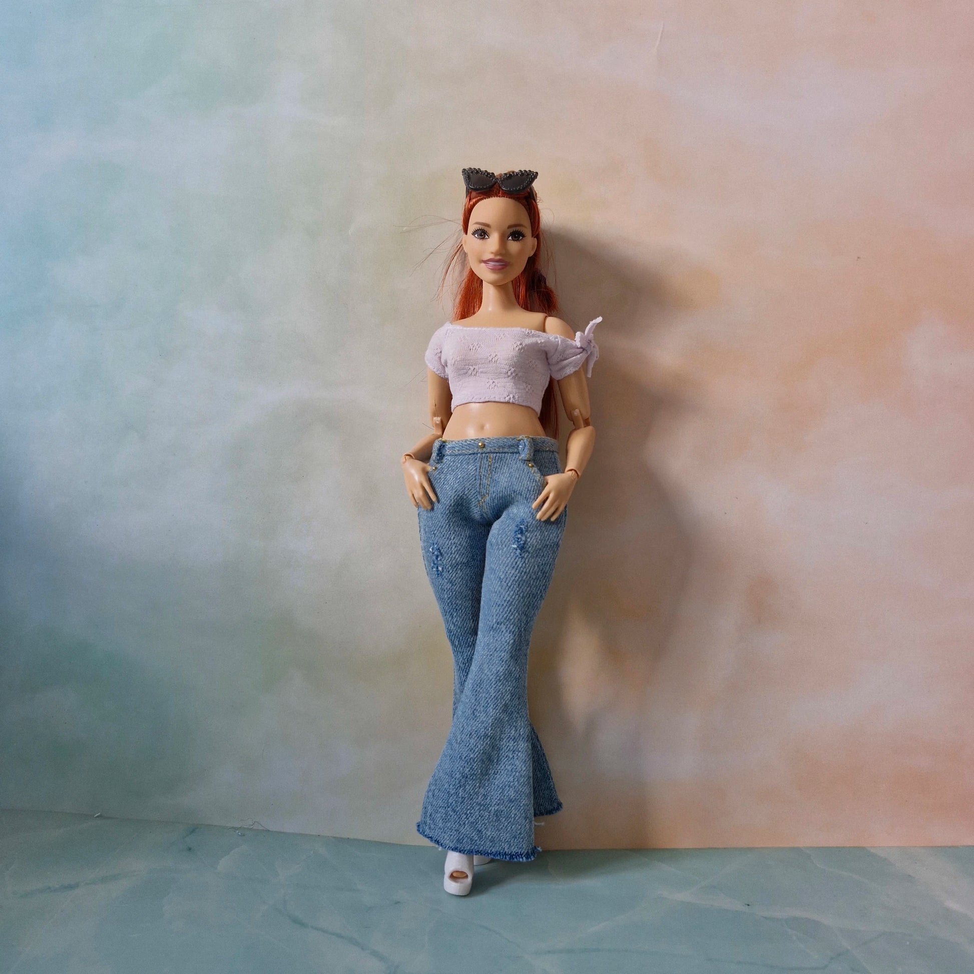Barbie curvy doll standing in blue flared jeans and white crop top with bow detail