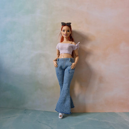 Barbie curvy doll standing in blue flared jeans and white crop top with bow detail