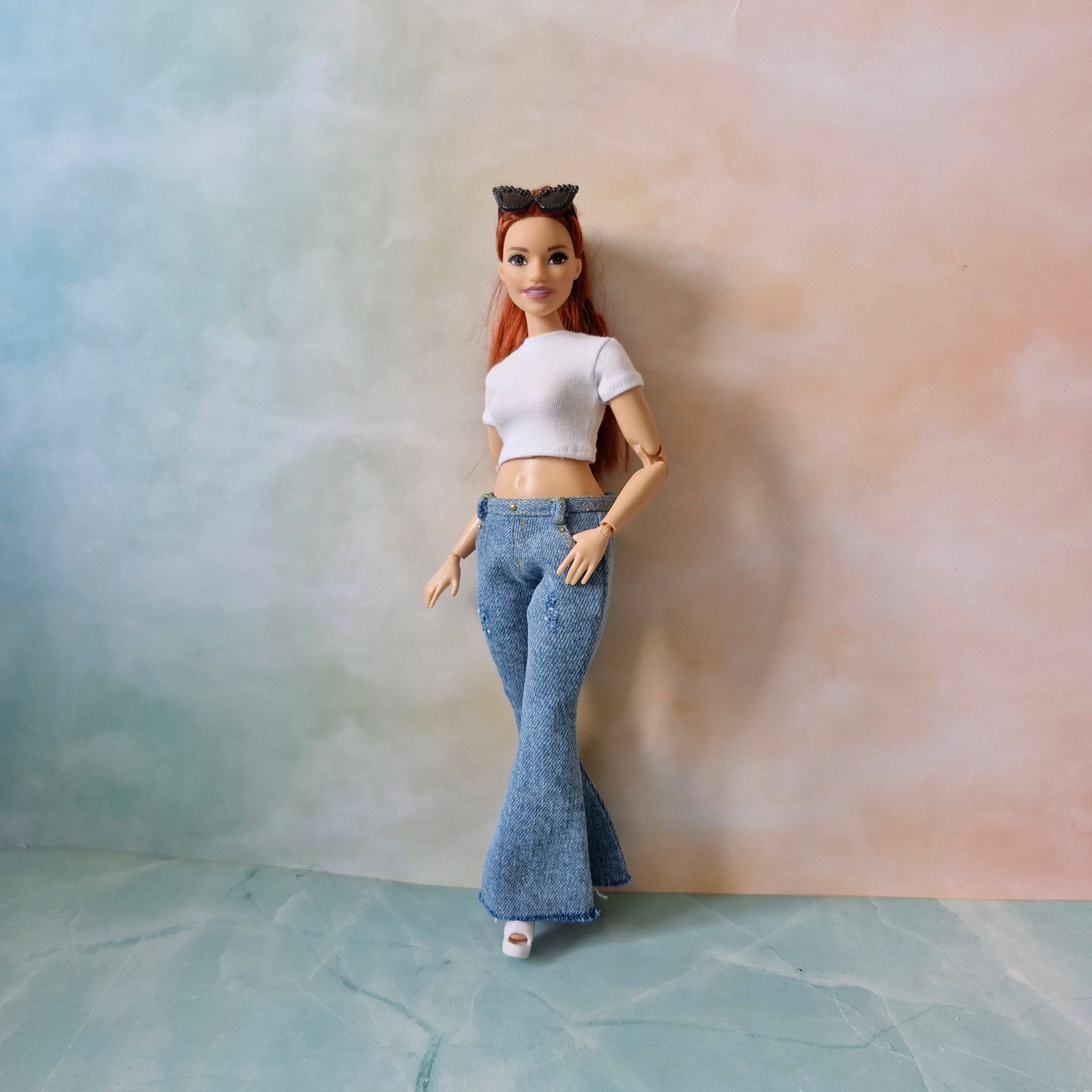 Barbie doll wearing a white top and blue jeans against a plain background