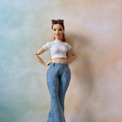 Barbie doll wearing a white top and blue jeans against a blurred background