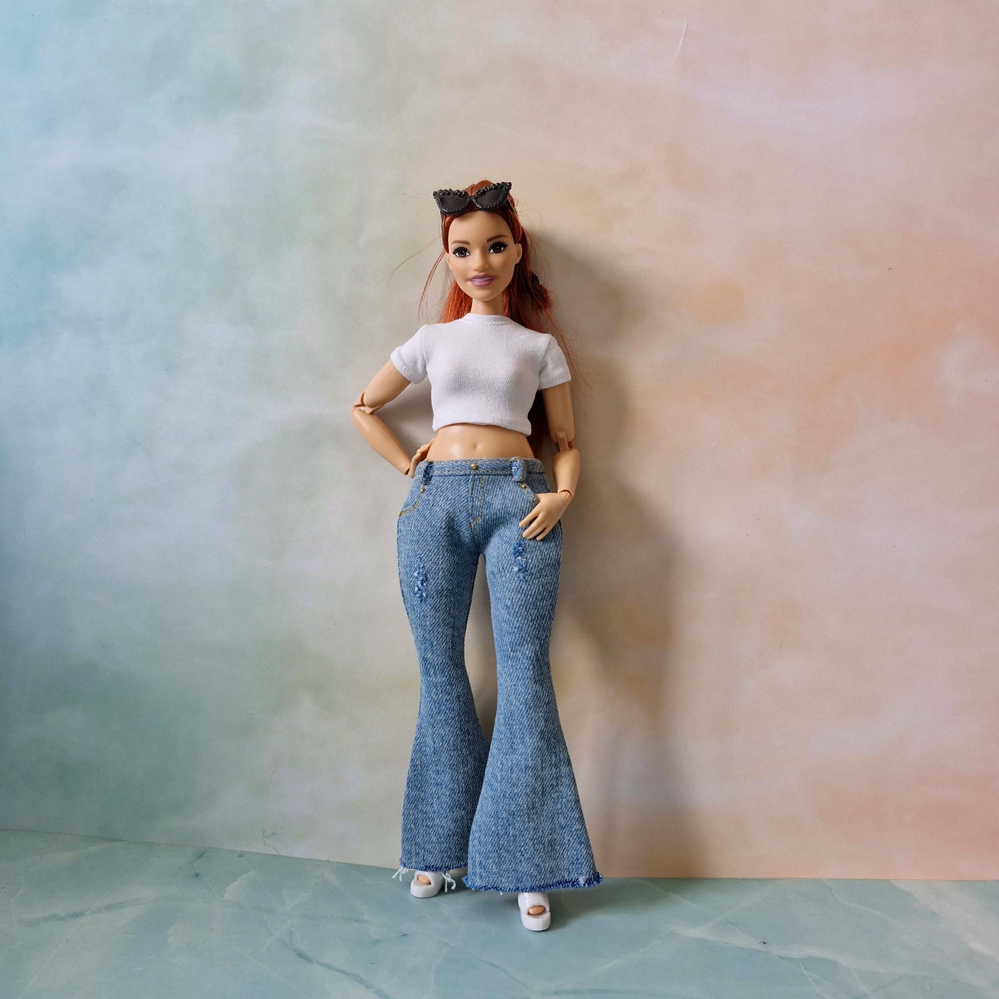 Barbie doll wearing a white top and blue jeans against a gradient background