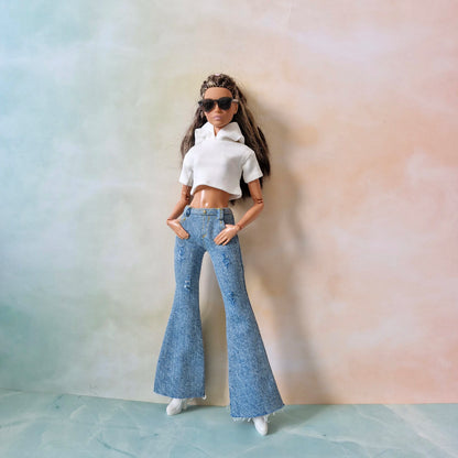 Barbie doll wearing a white top and blue jeans against a pastel background