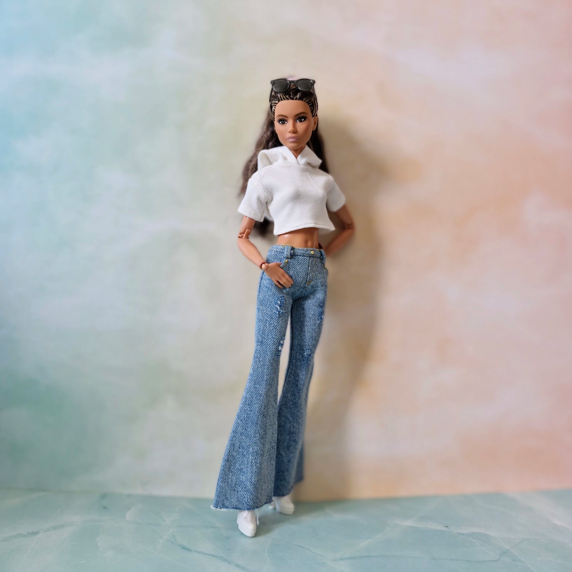 Barbie doll wearing a white top and blue jeans against a gradient background
