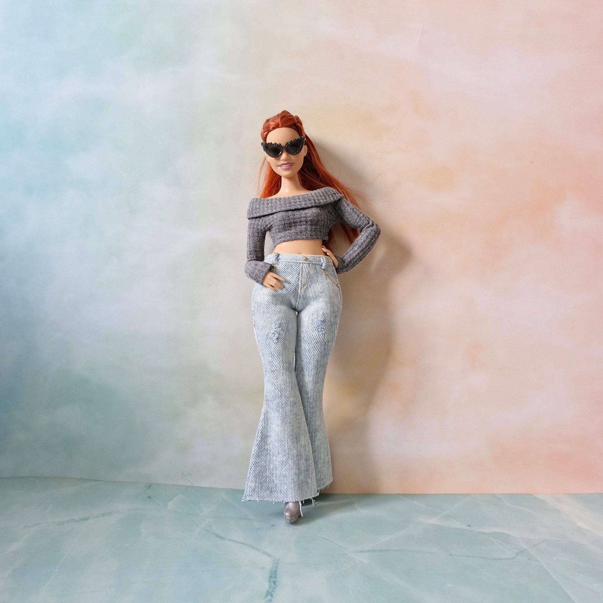 Curvy Barbie doll standing in gray knit top and light washed jeans