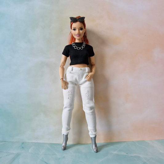 Barbie doll with black top and white pants against a gradient background