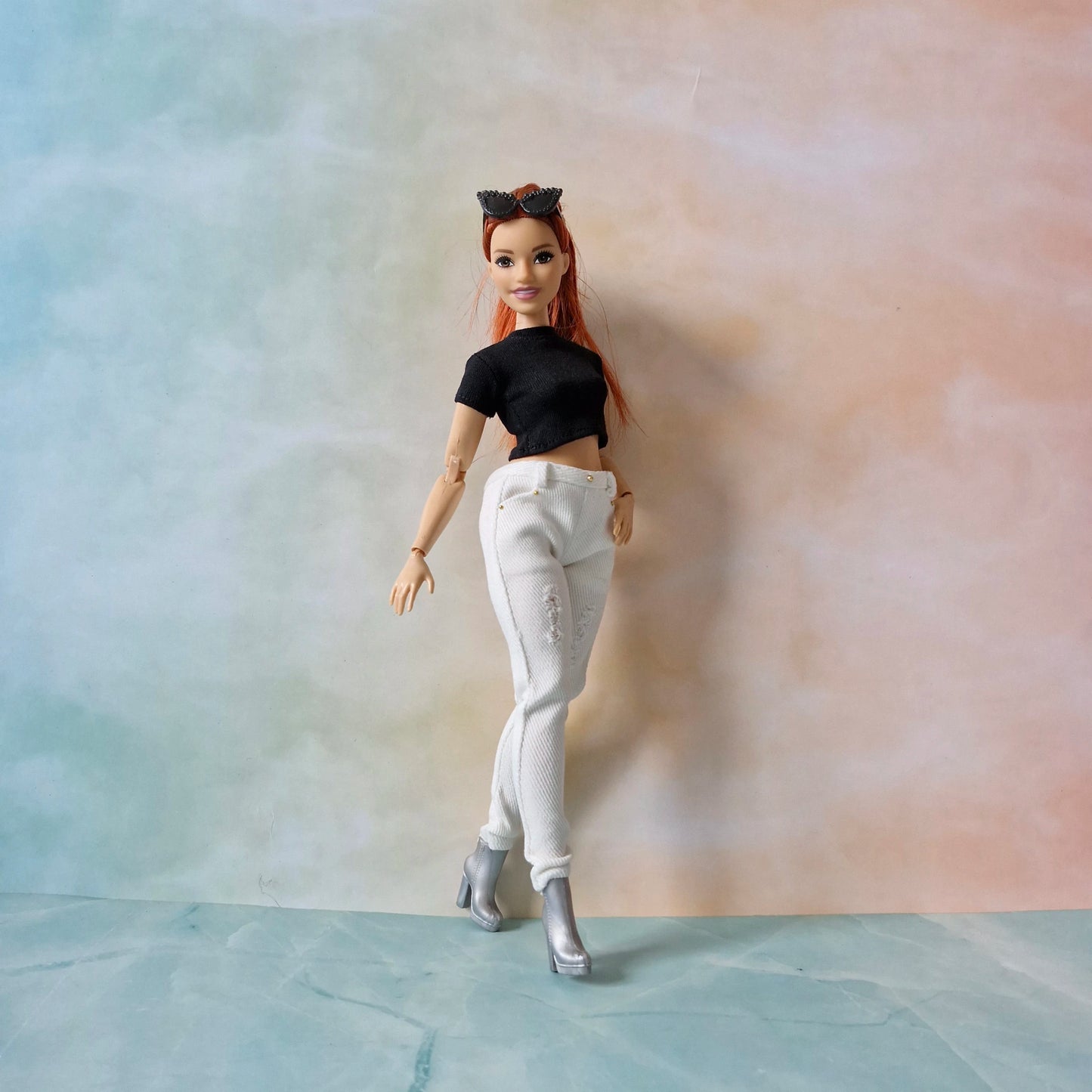 Barbie doll with red hair and black top against a gradient background