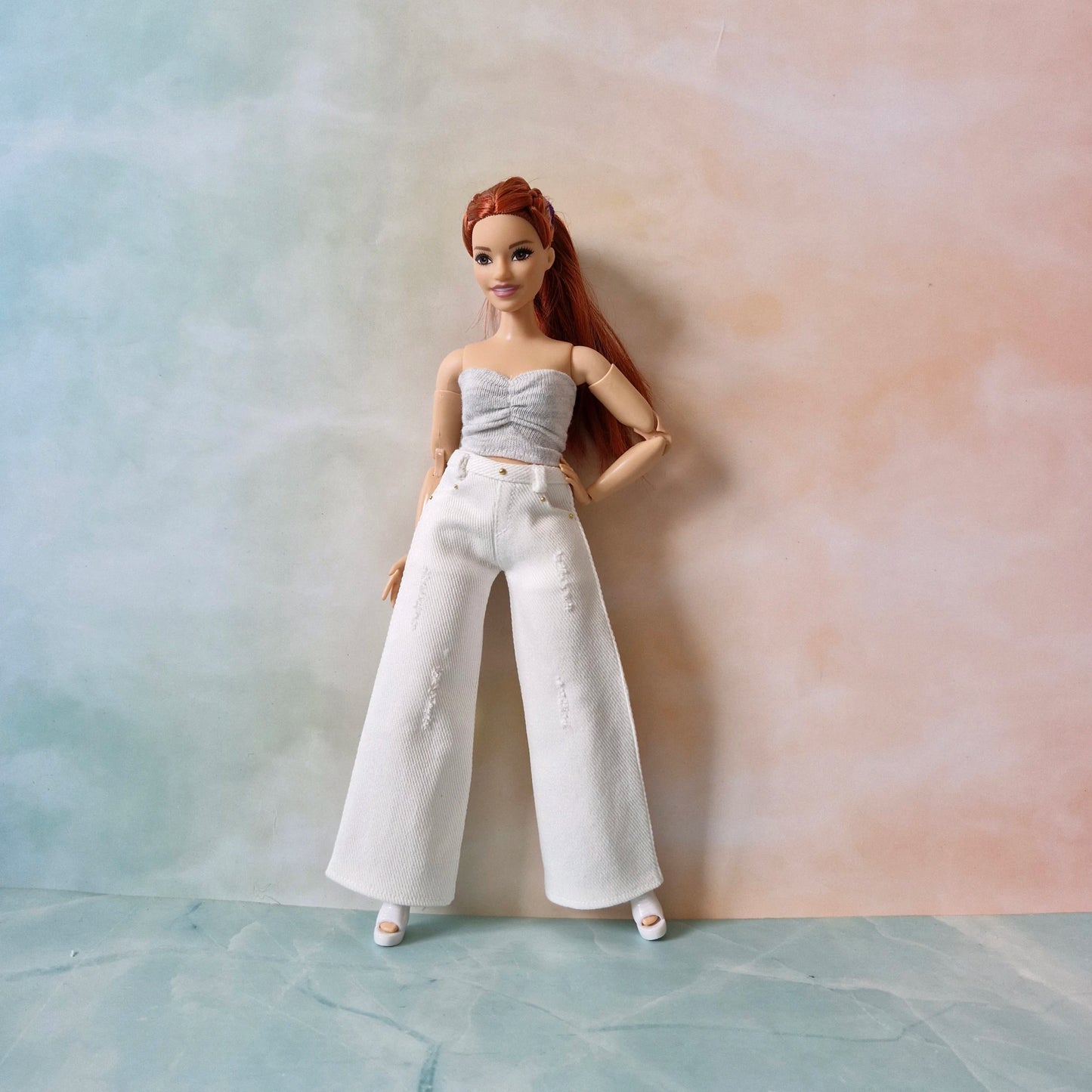 Curvy Barbie posing in white jeans and gray strapless top