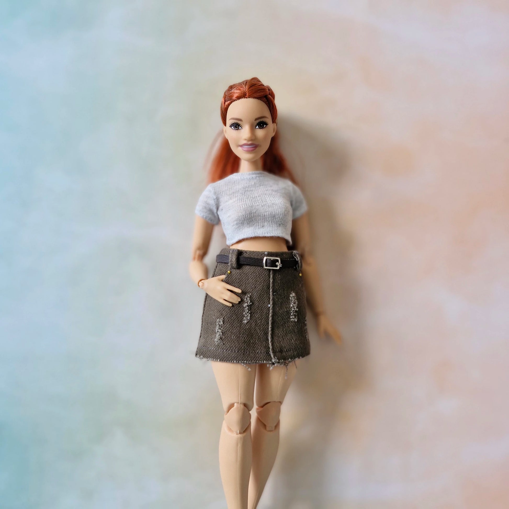 Curvy Barbie close-up in gray top and dark skirt with belt