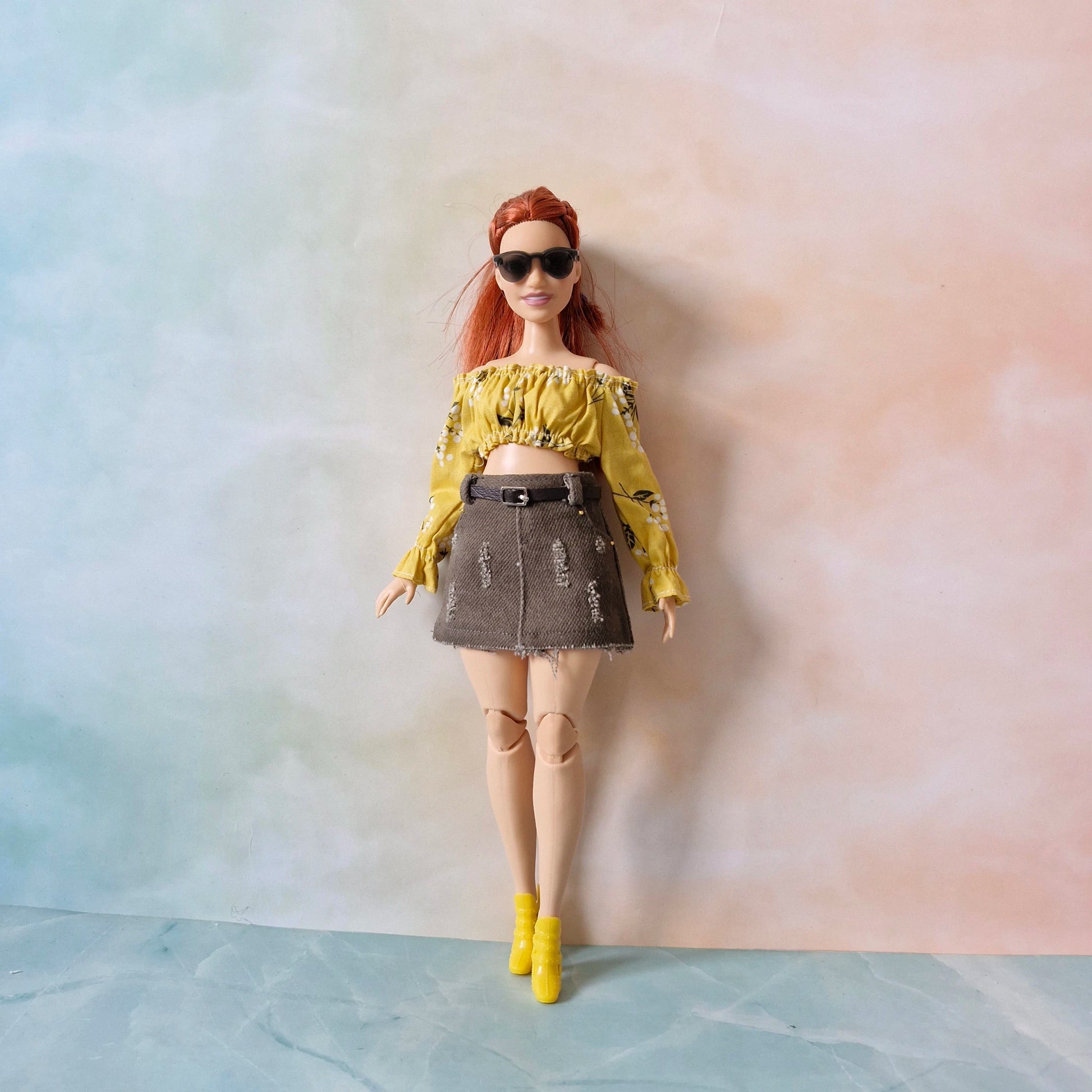 Doll wearing a yellow top and denim skirt against a gradient background