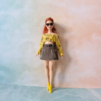 Doll wearing a yellow top and denim skirt against a gradient background