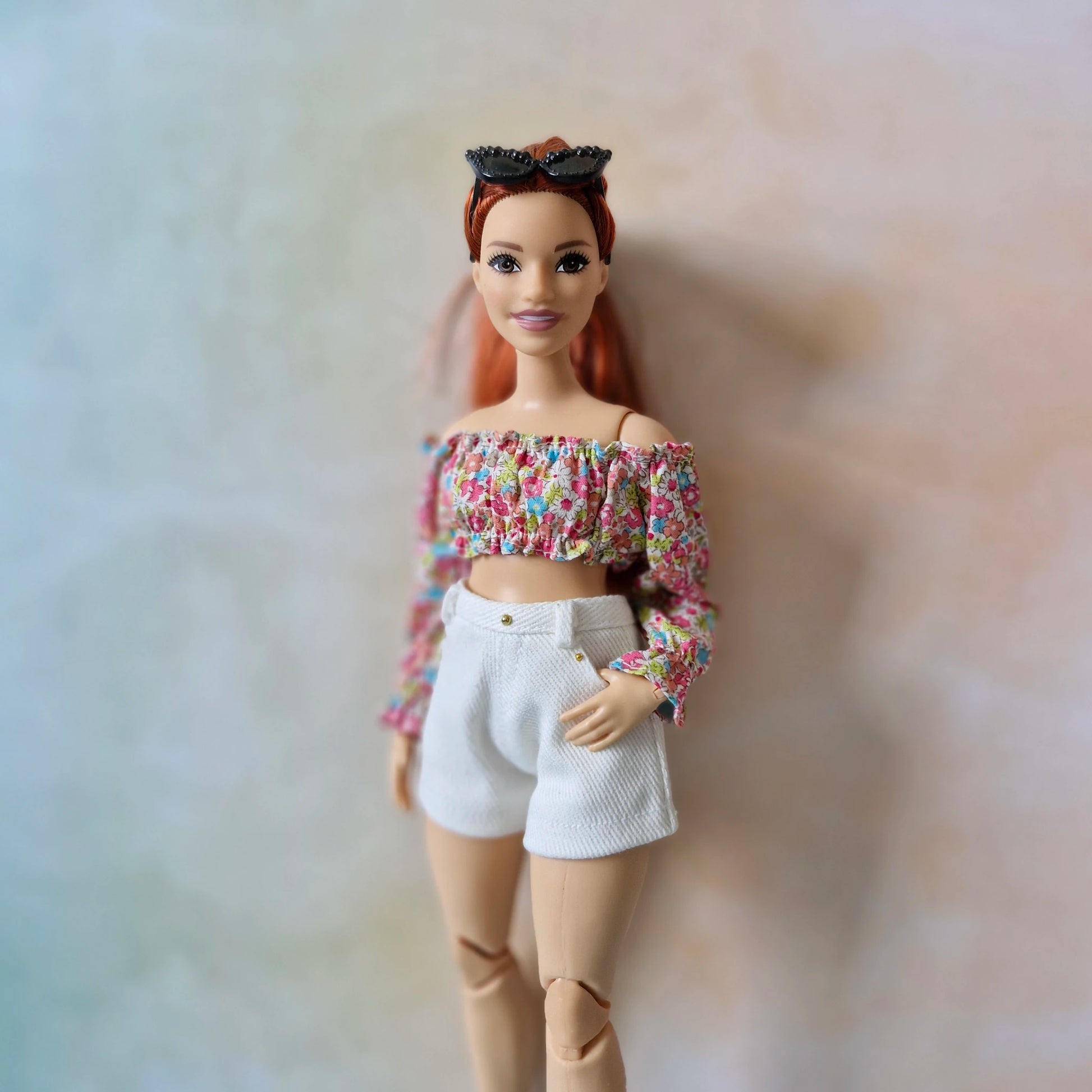 Curvy Barbie doll modeling a handmade multi-color floral top with white shorts.
