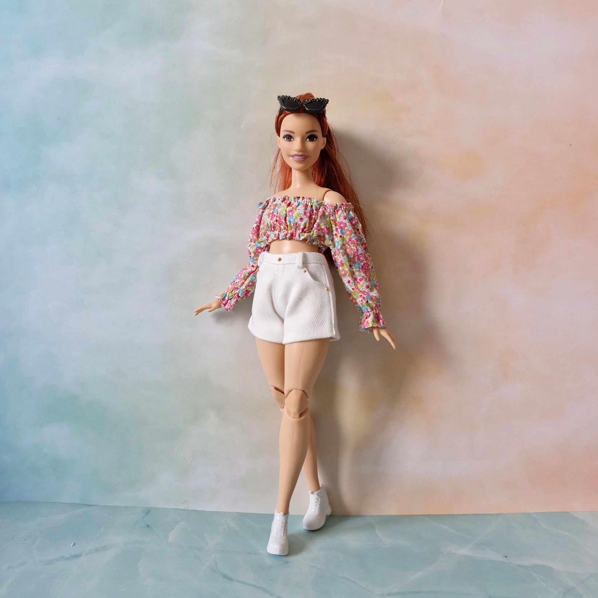Full view of Curvy Barbie wearing a long-sleeve floral top and white shorts.

