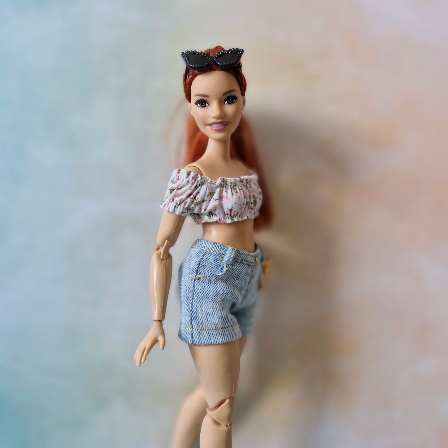 Side view of Curvy Barbie doll in a handmade pink floral top and denim shorts.
