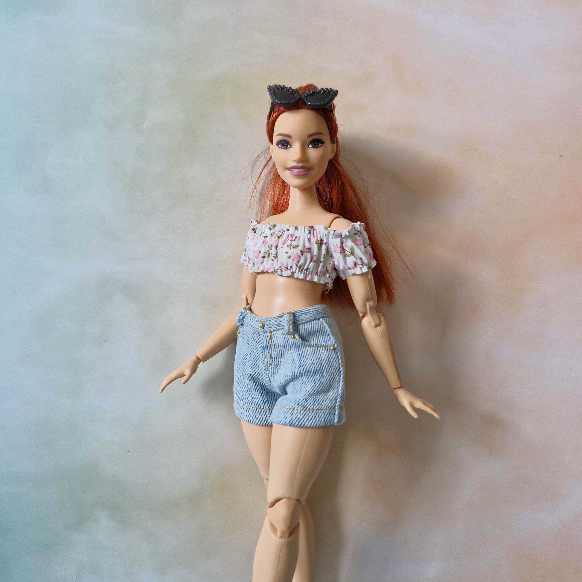 Full view of Curvy Barbie wearing a pink floral crop top and denim shorts.
