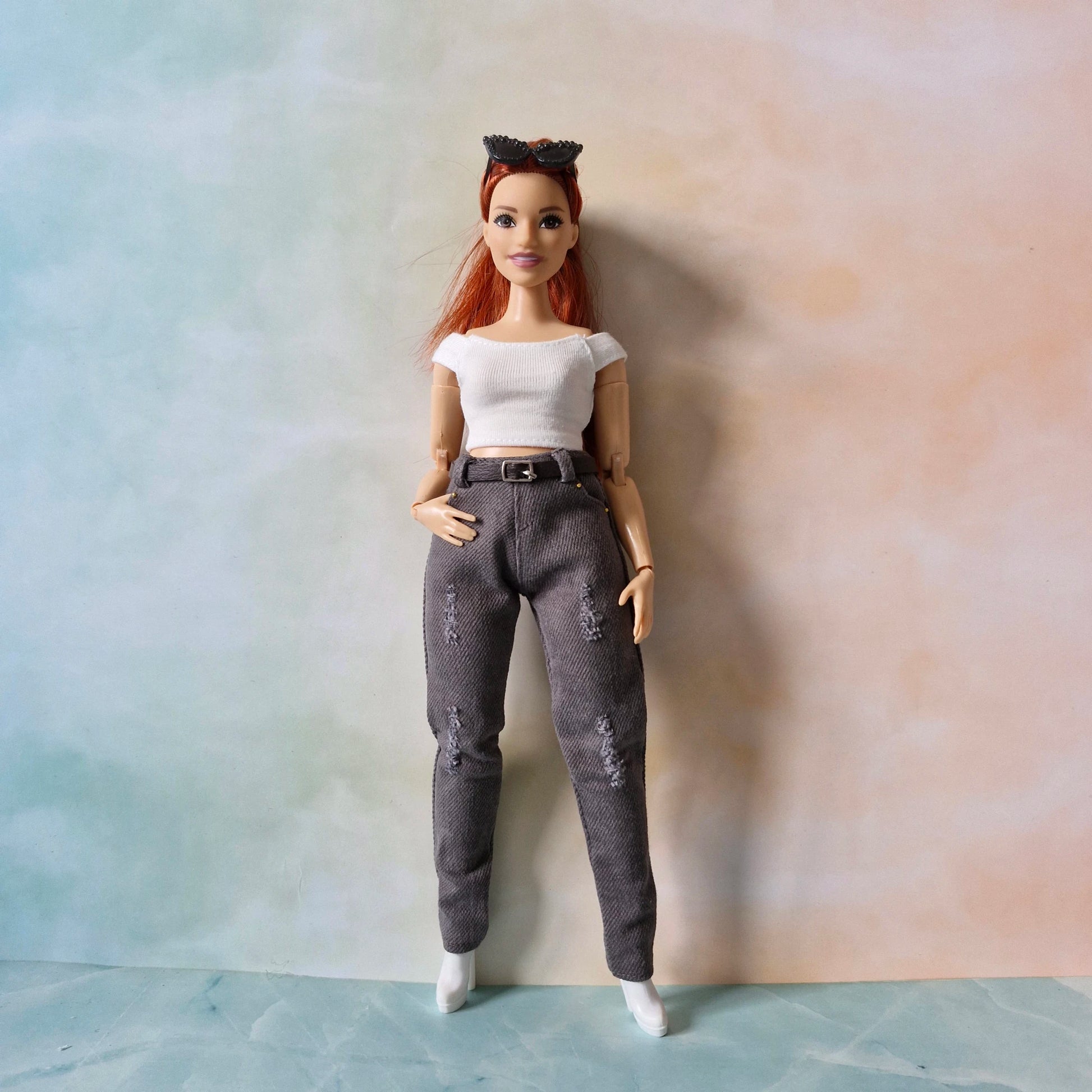Curvy Barbie doll with red hair and a white top standing against a plain background
