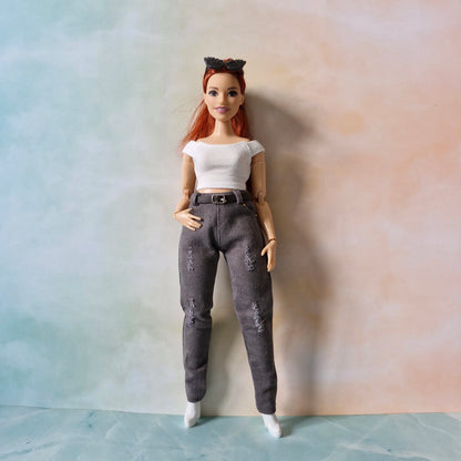 Curvy Barbie doll with red hair and a white top standing against a plain background
