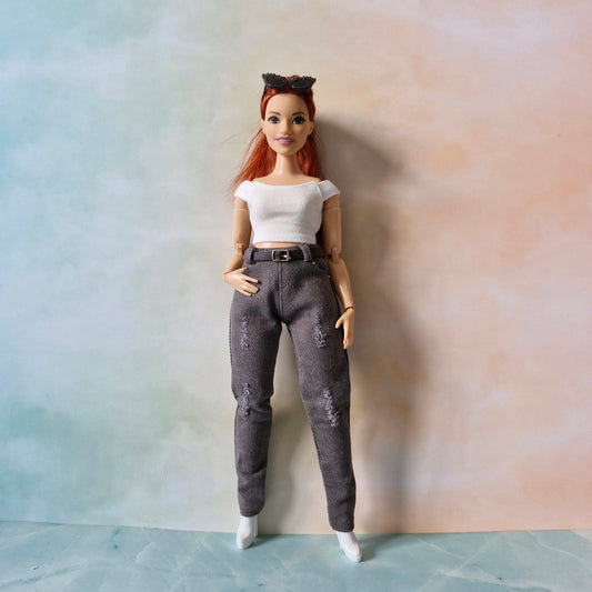 Curvy Barbie doll with red hair and a white top standing against a plain background