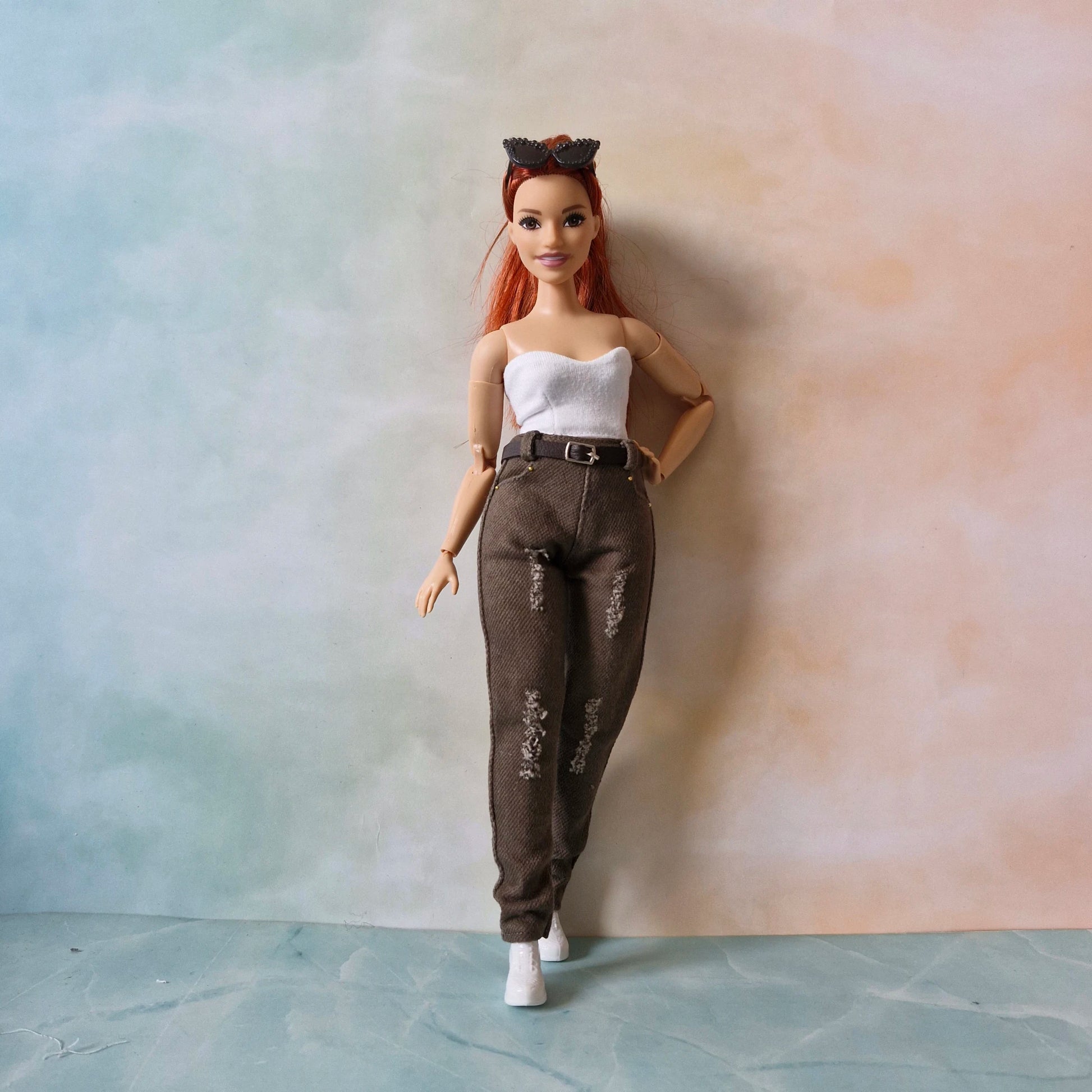 Curvy Barbie doll with red hair and white top standing against a gradient wall.