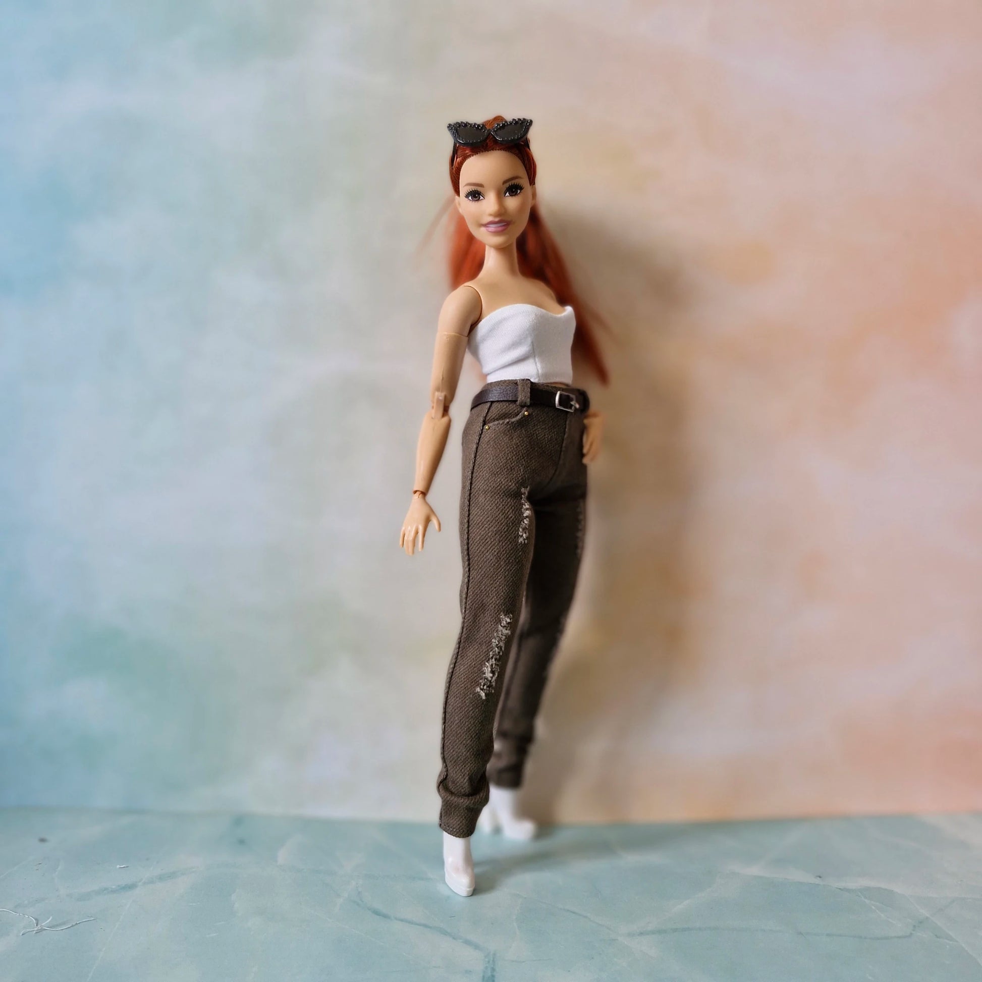 Curvy Barbie doll wearing a white top and brown pants with a blurred background