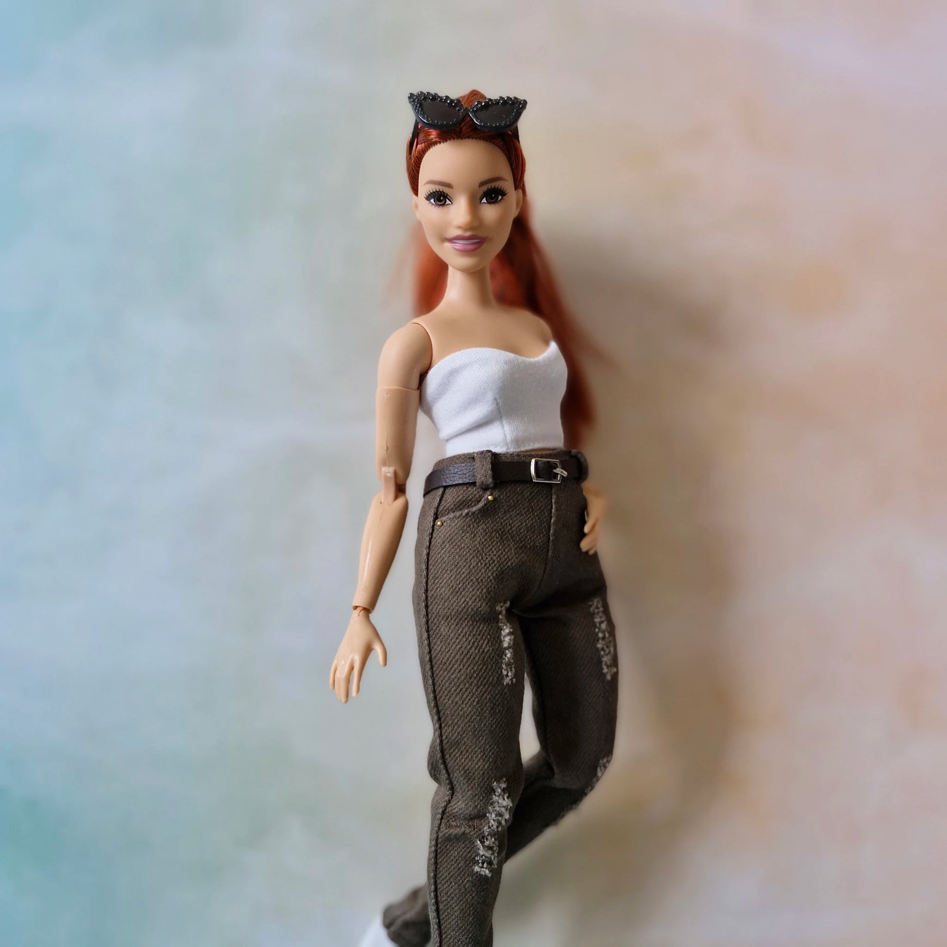 Curvy Barbie doll with red hair and a white top on a gradient background