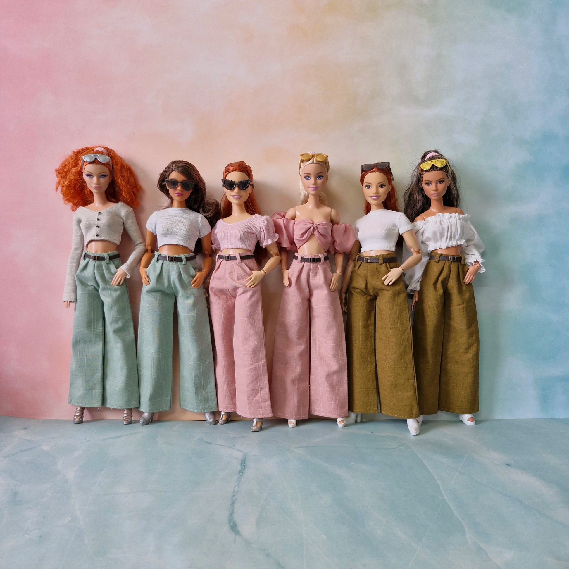 Six dolls in different outfits standing against a gradient background