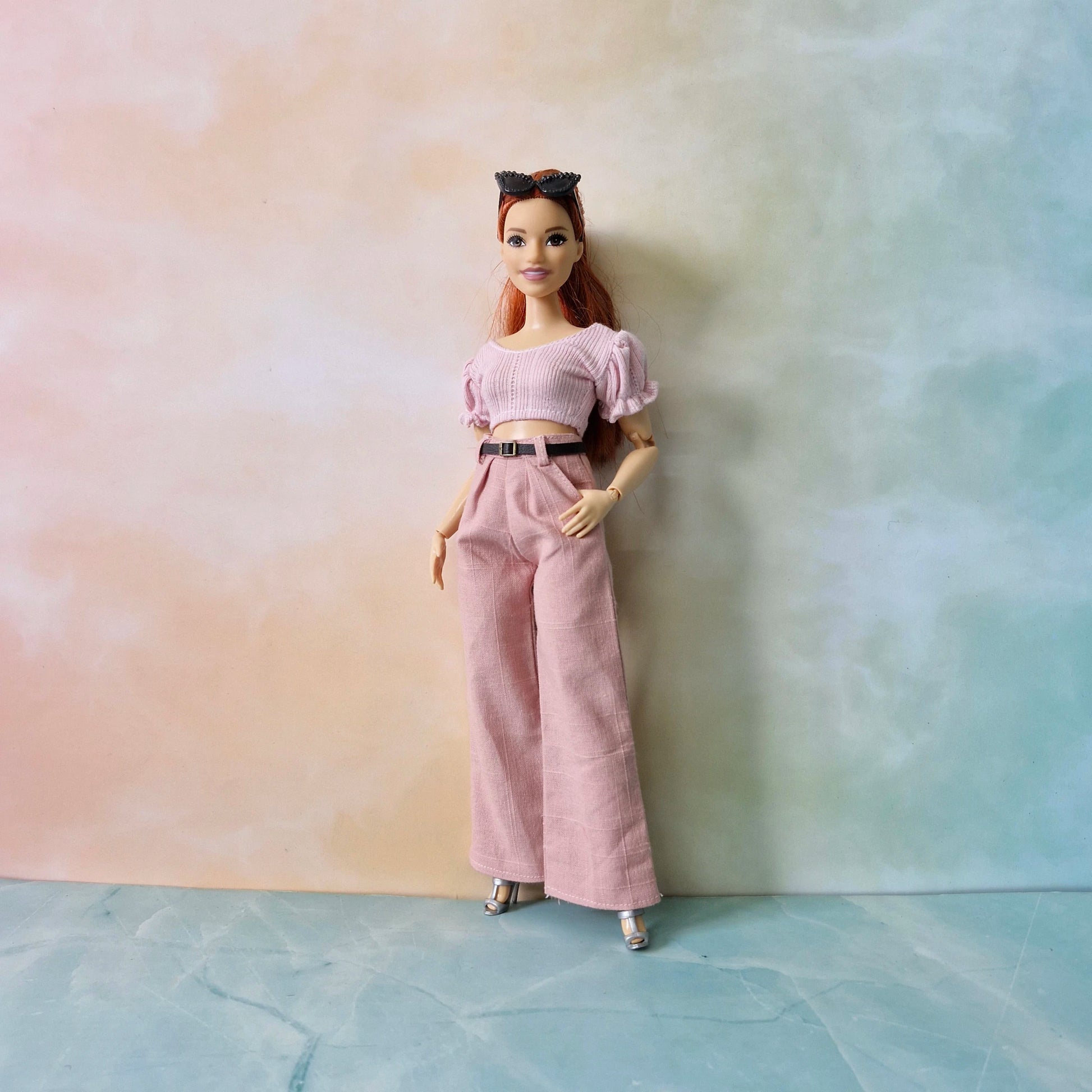 Barbie doll in pink outfit against a gradient background