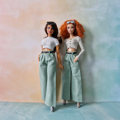 Two dolls wearing matching outfits against a gradient background