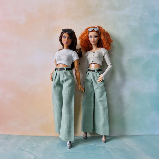 Two dolls wearing matching outfits against a gradient background