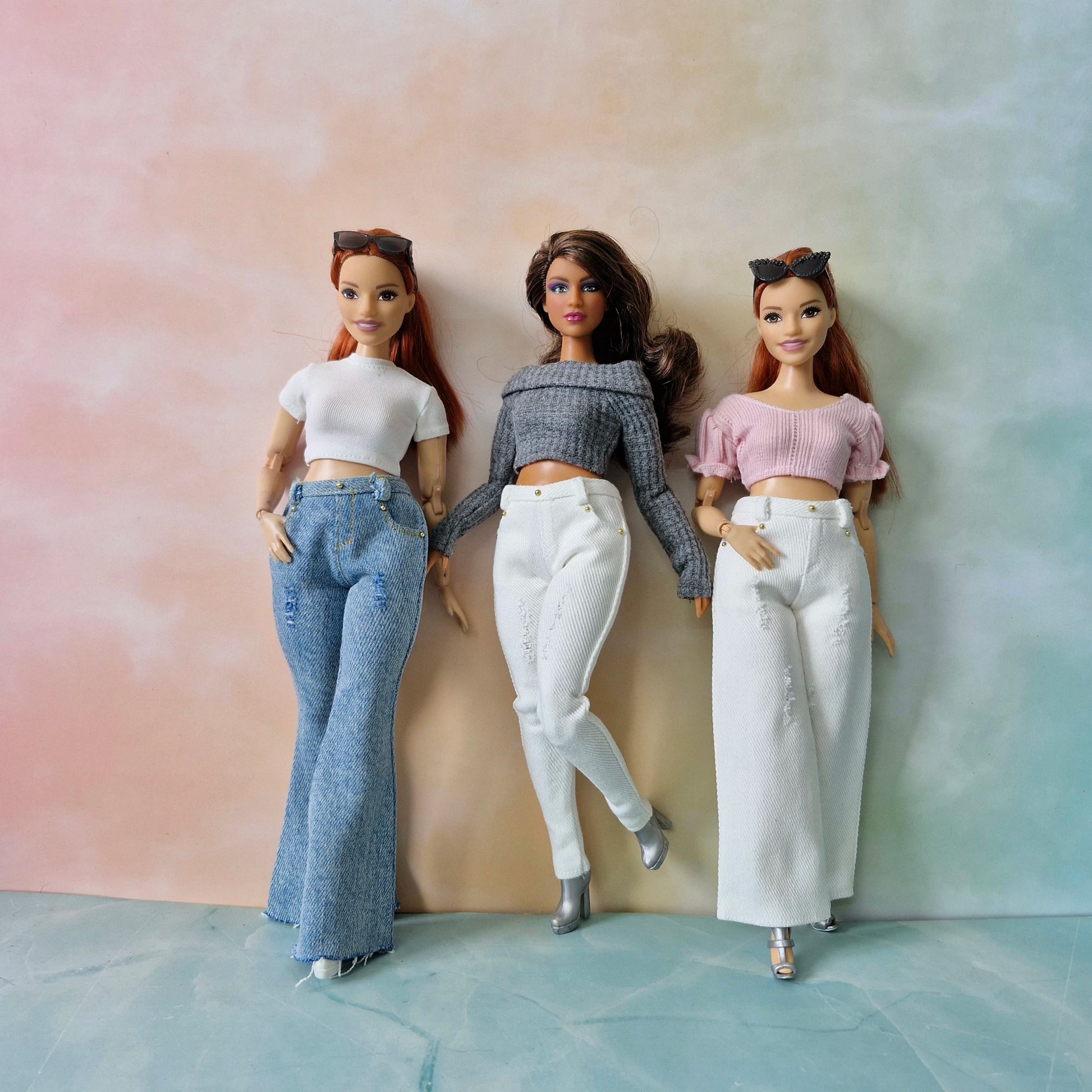 Three dolls in casual outfits against a pastel gradient background