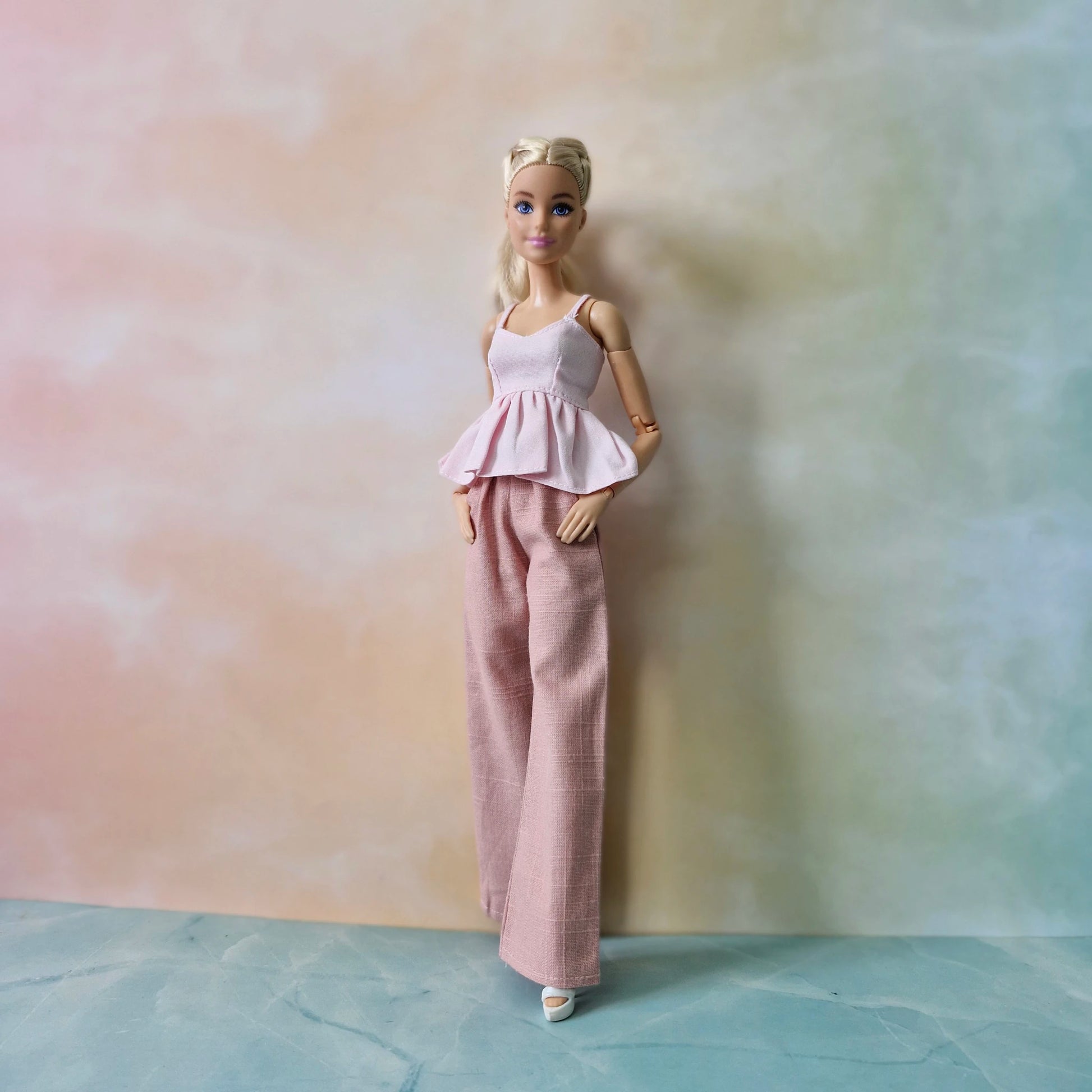 Barbie doll wearing a pink outfit against a pastel gradient background
