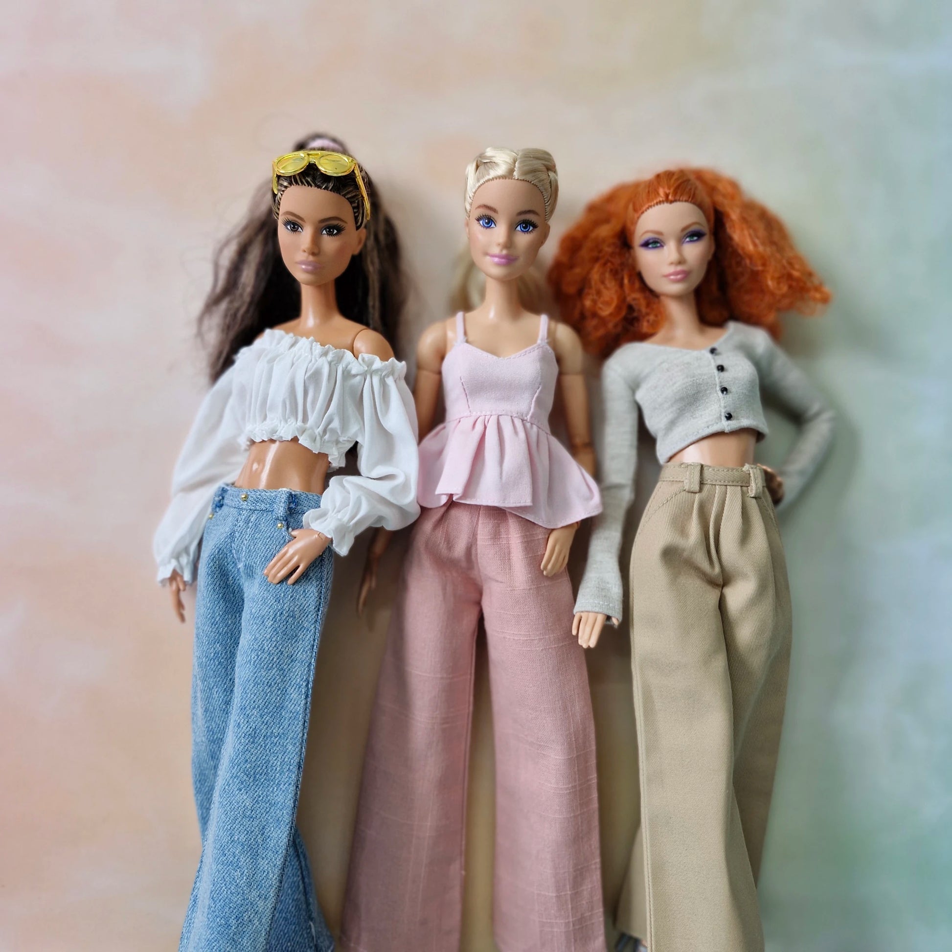 Three dolls with different hairstyles and outfits against a gradient background
