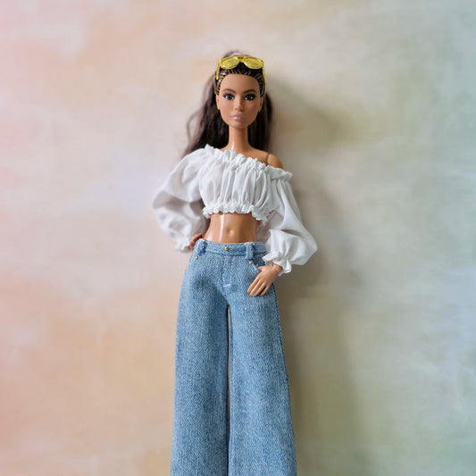 Barbie doll wearing a white top and blue jeans against a soft, multicolored background
