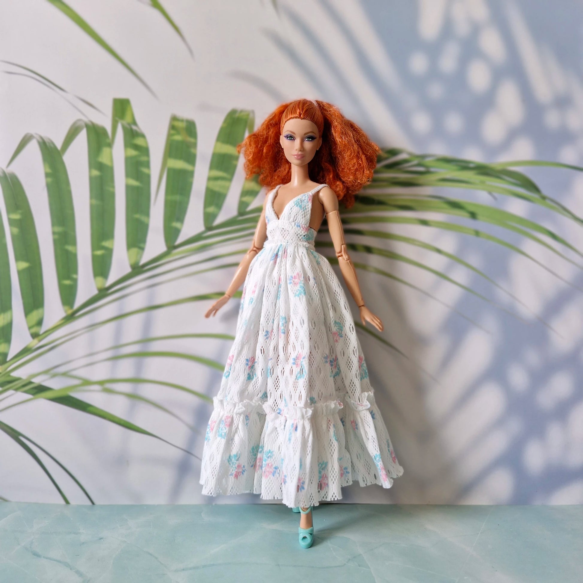 Barbie doll wearing white lace floral maxi dress with deep V neck and ruffles