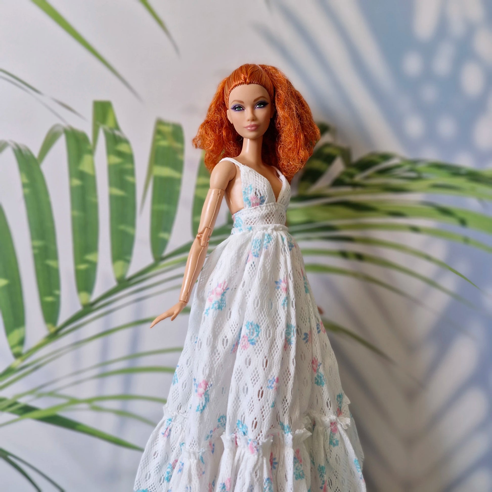 Barbie doll in a white floral dress with a leafy background