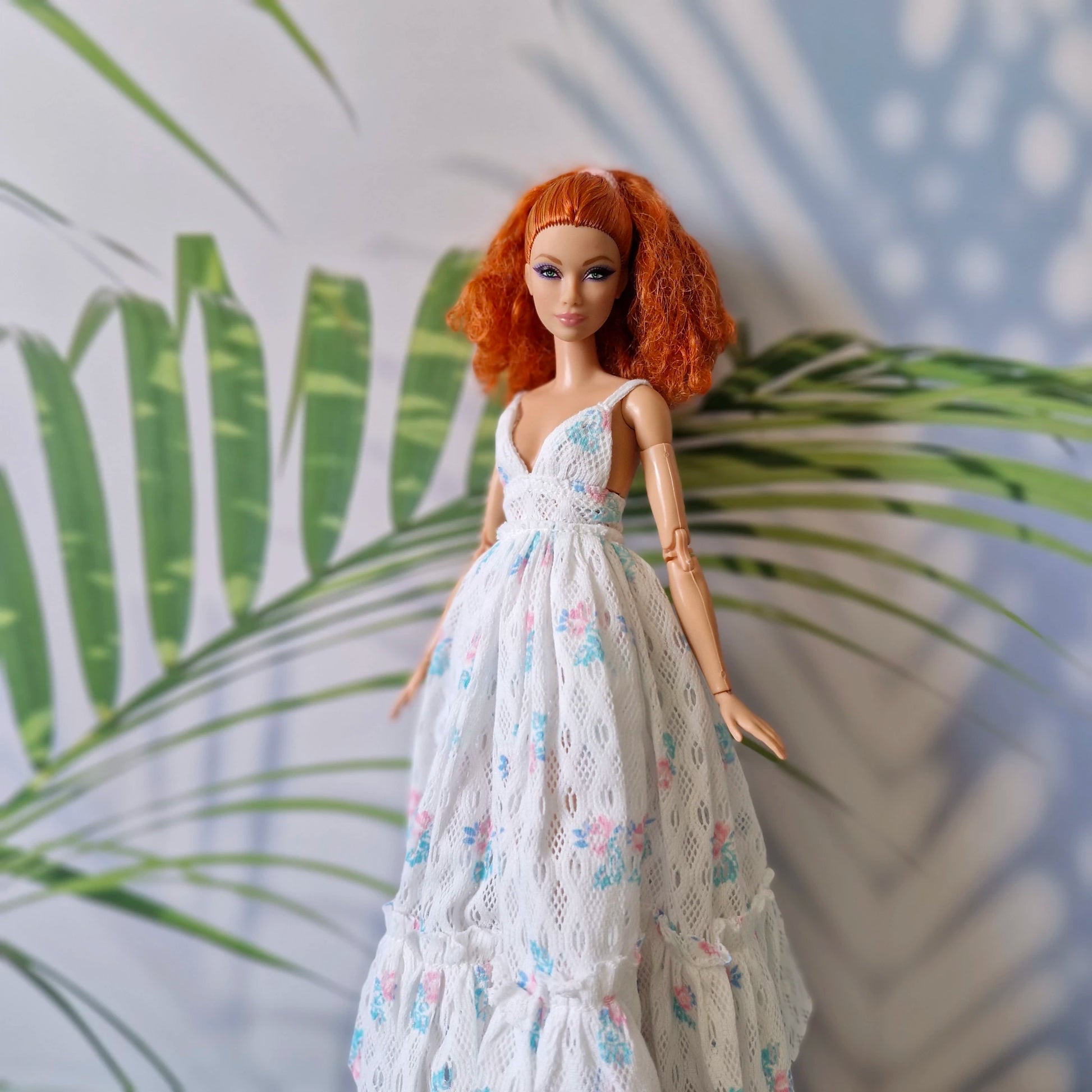 Barbie doll in a white floral dress with a leafy background