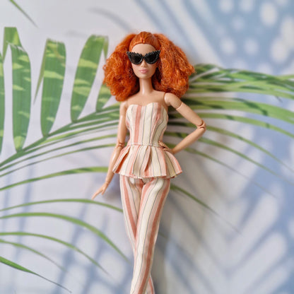 Barbie doll in a striped outfit with sunglasses against a leafy background