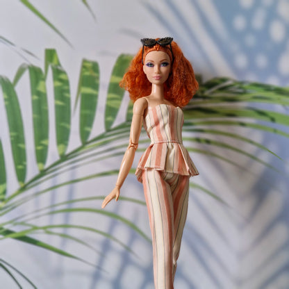 Barbie doll in a striped outfit with a tropical leaf background