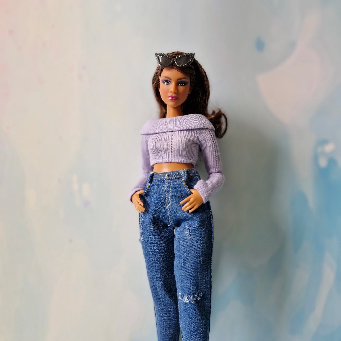 Barbie doll wearing a purple top and blue jeans against a light background