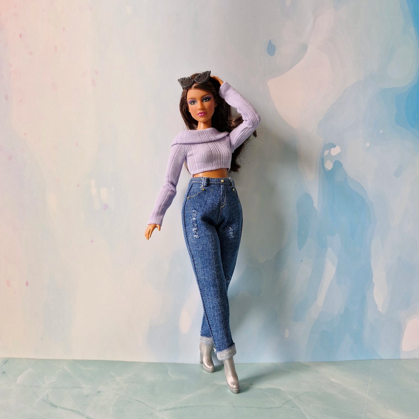 Barbie doll wearing a purple top and blue jeans against a light background