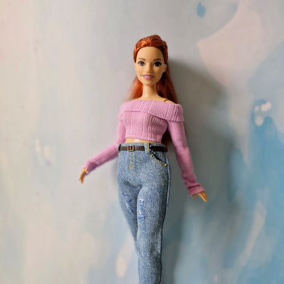 Barbie doll wearing a pink top and blue jeans against a light background