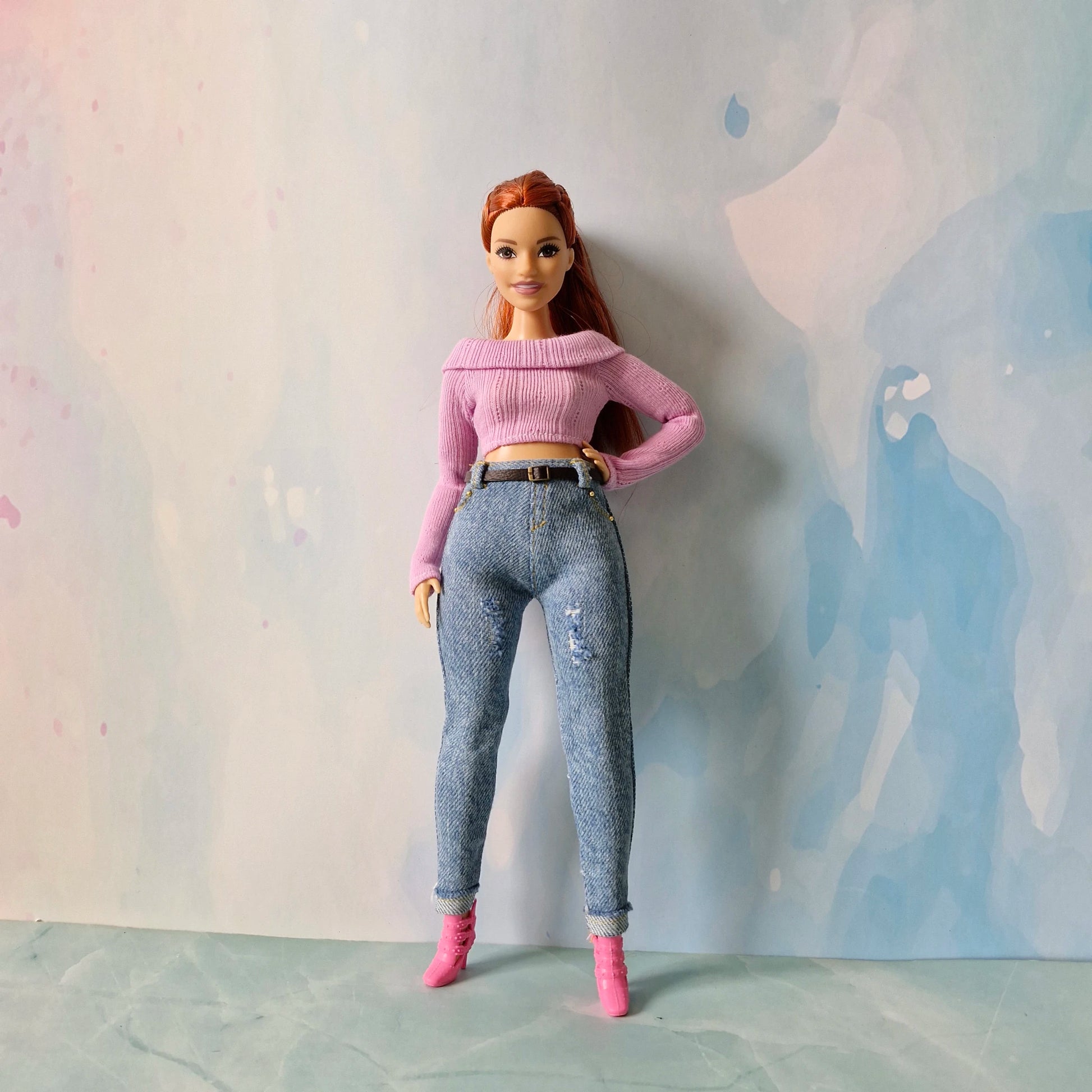 Barbie doll wearing a pink sweater and blue jeans against a light background