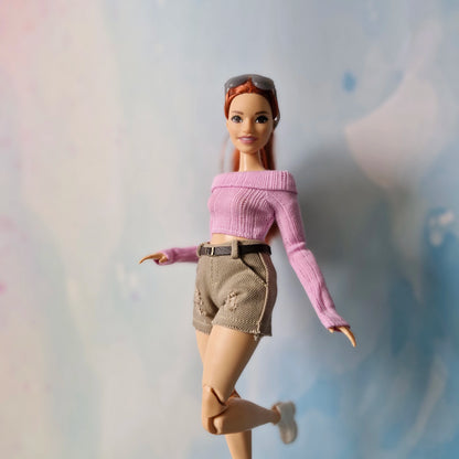 Barbie doll wearing a pink sweater and beige shorts on a light background